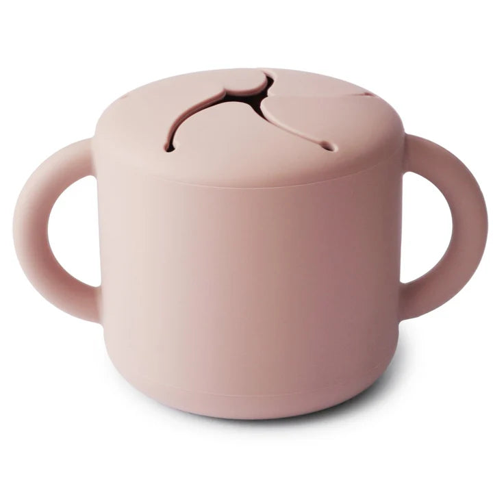 Mushie Snack Cup in Blush – auslaufsicherer Silikon-Snackbecher für Babys und Kleinkinder mit weichen Lamellenöffnung, ideal für unterwegs, selbstständiges Snacken und Baby-led Weaning. BPA-freier Kinder Snackbecher in Blush Design.