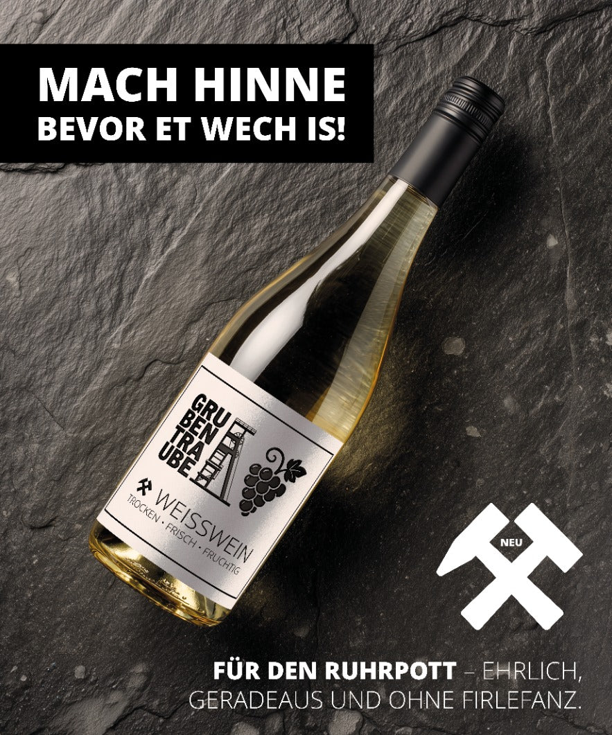 Gruppentraube Weißwein Flasche liegend auf dunklem Stein – trockener, frischer Ruhrpott-Wein mit Etikett „Grubentraube“ und Slogan „Mach hinne bevor et wech is – für den Ruhrpott, ehrlich, geradeaus und ohne Firlefanz“.
