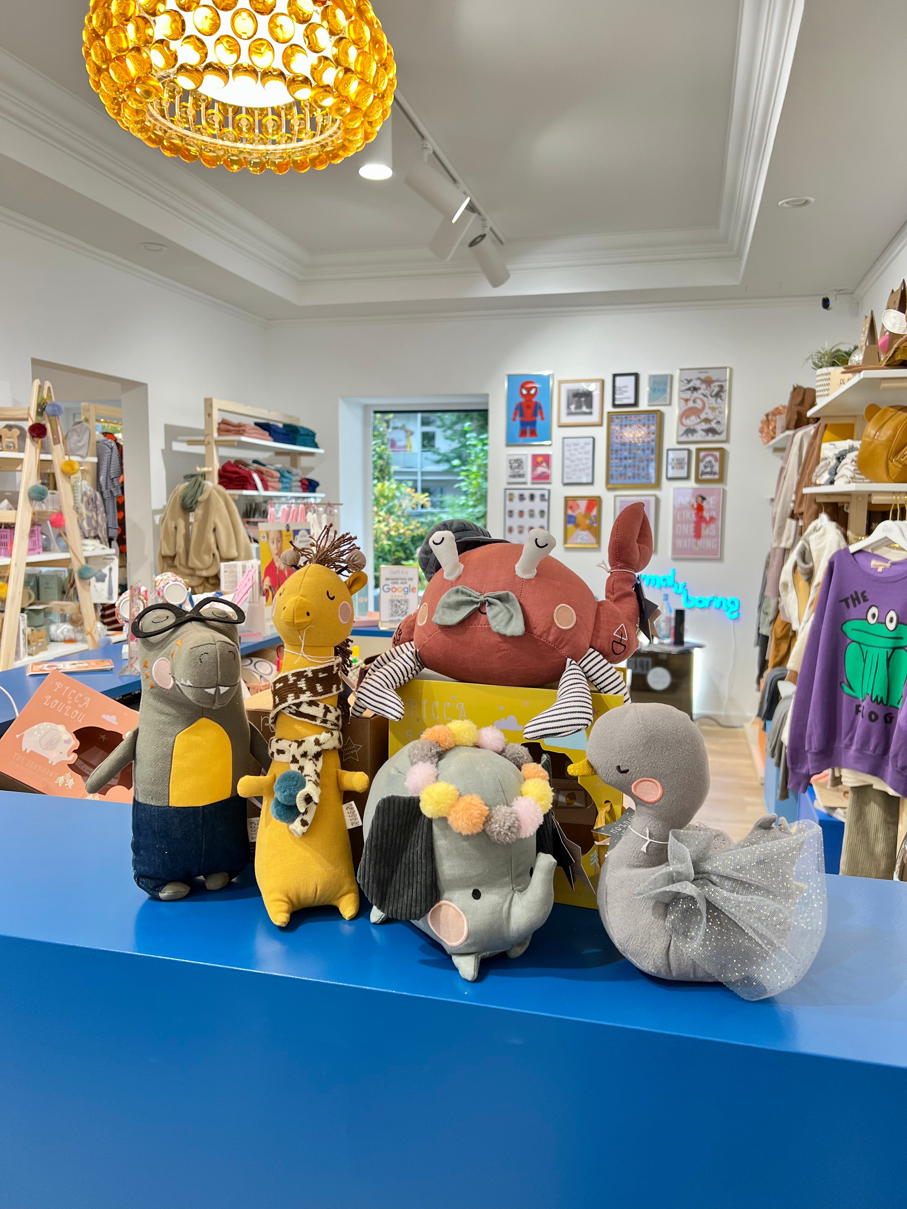 Inenansicht des Concept Stores Charlie & Lu, präsentiert liebevoll arrangierte Kinderbekleidung in einem stilvollen Ambiente; im Vordergrund hochwertige Kuscheltiere auf einem blauen Tresen